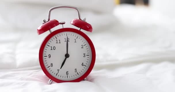 Reloj despertador rojo para las siete de la mañana está en la cama en el dormitorio — Vídeo de stock