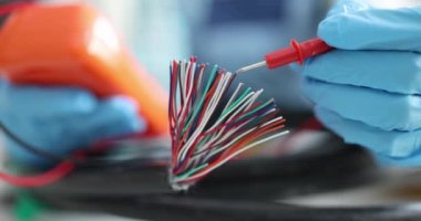 Eldivenli elektrikçi çok renkli elektrik kablolarını test ediyor
