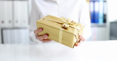 Kişi, altın ambalajlı bir kutuda hediye verir ve selam verir.