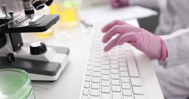 Scientist in gloves works on laptop in laboratory. — Stock Video