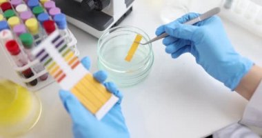 Bilim adamı cam bardaktaki suyu test etmek için PH test kiti kullanıyor.