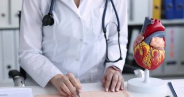 Kardiyolog klinikteki hastanın elektrokardiyogramını inceliyor.