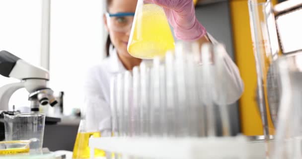 Ilmuwan mengaduk cairan berminyak kuning dalam labu di laboratorium closeup — Stok Video