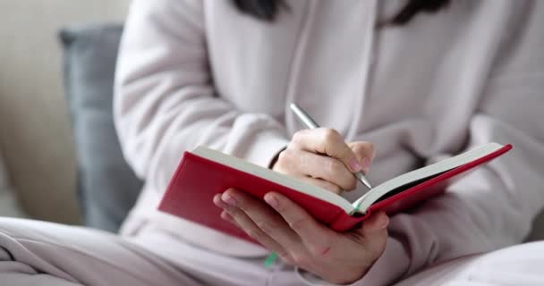 Kvinna författare skriver anteckningar i dagbok medan du sitter på soffan — Stockvideo