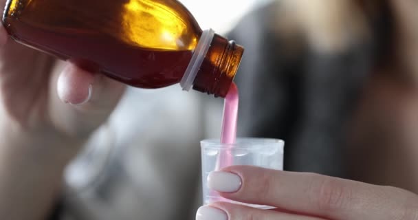 Woman pours cough syrup into measuring cup closeup — Stock Video