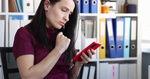 Mujer joven triste mira en la pantalla del teléfono inteligente — Vídeos de Stock