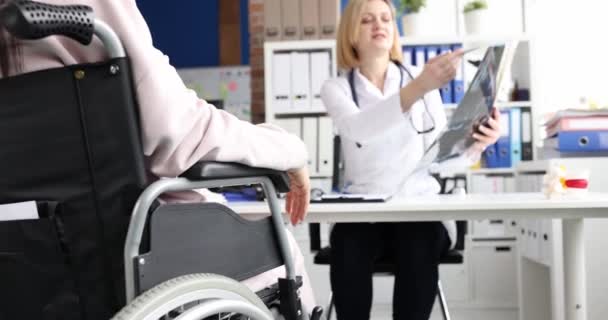 Dokter memeriksa x-ray tulang belakang dengan pasien di kursi roda — Stok Video
