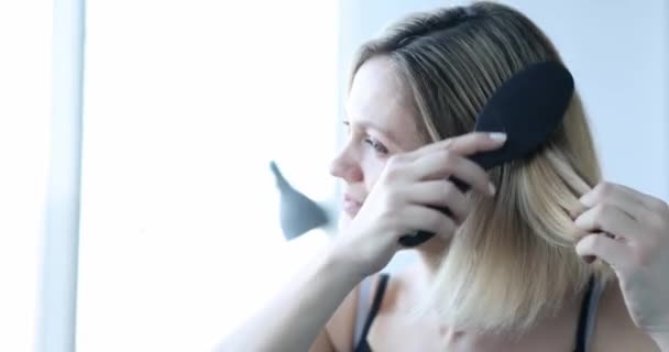 Разочарованная женщина расчесывает волосы и смотрит много выпавших волос 4К фильм — стоковое видео