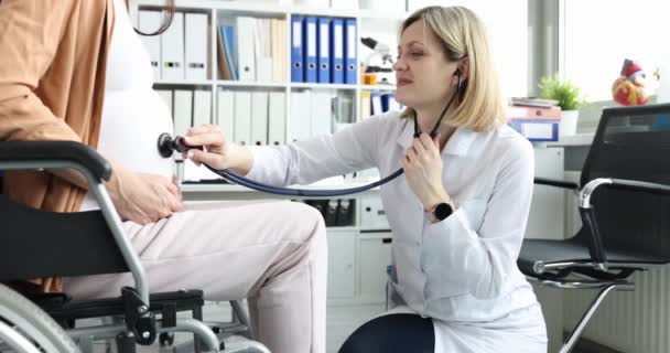 Médecin écoute avec stéthoscope au rythme cardiaque foetal à la femme enceinte en fauteuil roulant dans le film clinique 4k — Video