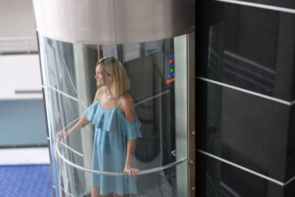 Joven mujer sonriente cabalgando en ascensor de cristal transparente —  Fotos de Stock
