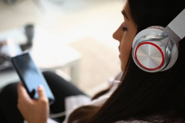 Kadın kulaklık takar, film izler ya da akıllı telefondan müzik dinler.