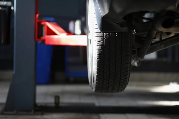 Automobile tire, part of automobile in service center, lifted car in air — Stock Photo, Image