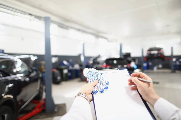 Männliche Arbeiter füllen Wartungsunterlagen aus, Blick auf Autowerkstatt — Stockfoto