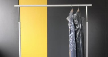 Gri arkaplanda beyaz askıda kıyafet koleksiyonu.