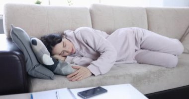 Kadın kanepede uyuyor ve sinir bozucu bir şekilde telefonu kapatıyor.