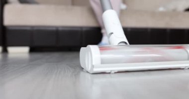 Kadın temizlikçi kadın oturma odasında yerleri süpürüyor.