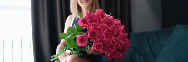 Ung vacker leende kvinna sitter med stor bukett rosor — Stockfoto
