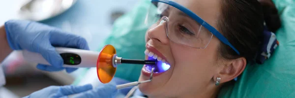 Dentista detém lâmpada dentária LED e instrumento na boca do paciente — Fotografia de Stock