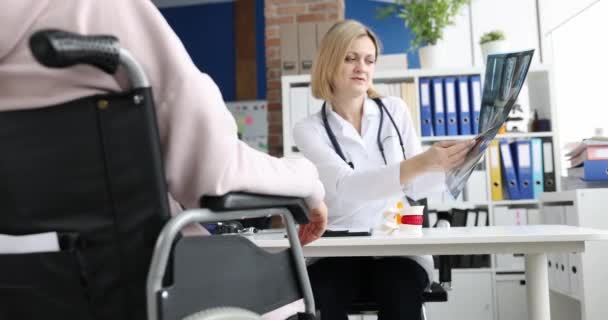 El médico examina una radiografía del paciente en silla de ruedas — Vídeo de stock