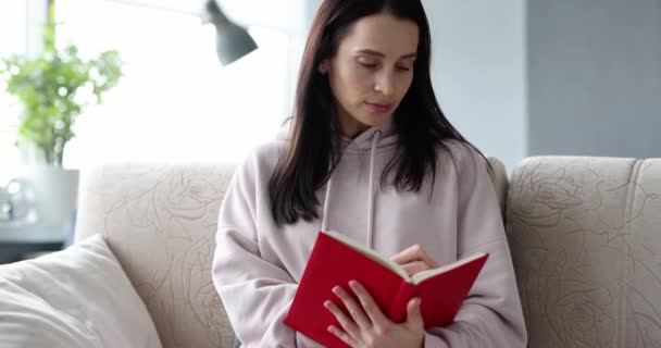 Kvinna skriver ner att göra-lista i dagbok medan du sitter på soffan — Stockvideo