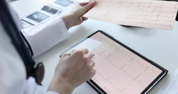 Cardiologist examines patient electrocardiogram on tablet — стоковое видео