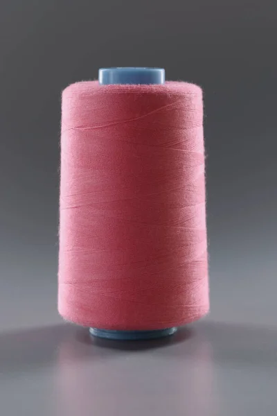 Нитка для одягу, рожева нитка кольору на сірій поверхні, пряжа для шиття — стокове фото