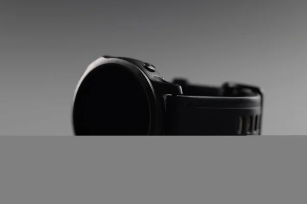 Dispositivo minimalista na moda, relógio de pulso masculino preto deitado sobre fundo cinza — Fotografia de Stock