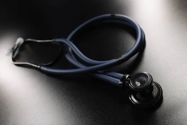 Medical stethoscope placed on dark surface, tool for patient diagnostic — Stock Photo, Image