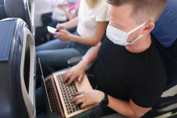 Man arbetar i luften, öppen laptop enhet, ansiktsmask skydd, upptagen frilansare på flykt — Stockfoto