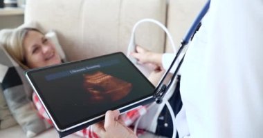 Hamile kadın evde ultrason cihazıyla doğum sonogramı yapıyor.