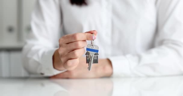 Person hält Hausschlüssel an Schlüsselanhänger in Form eines Hauses — Stockvideo