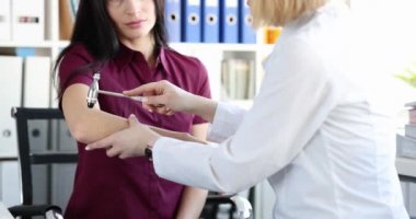 Doktor çekiçle hastanın dirseğini yakın plan çekiçle kontrol ediyor.