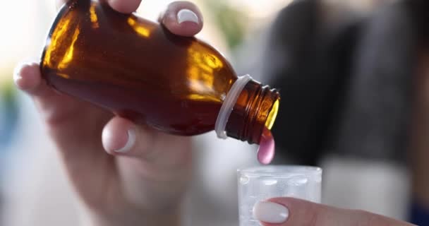 Vrouwelijke handen gieten medische siroop in het meten van plastic beker — Stockvideo
