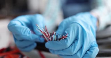 Eldivenli elektrikçinin elleri çok renkli elektrik kablolarıyla yakın plan.
