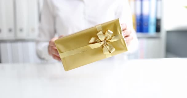 Persoon houdt geschenkdoos in gouden verpakking met strik — Stockvideo