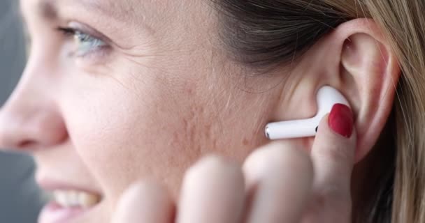 Ασύρματα λευκά ακουστικά bluetooth στο γυναικείο αυτί — Αρχείο Βίντεο