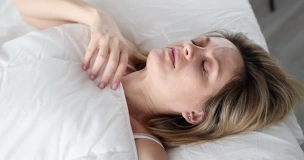Kvinna ser i skräck under täcket på sängen närbild — Stockvideo