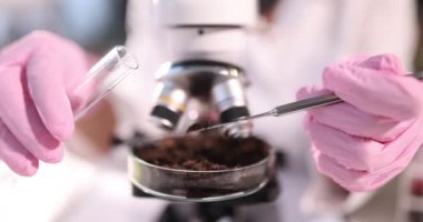 Araştırmacı elinde toprak olan cam şişeyi tutuyor.