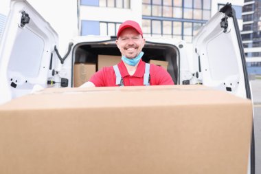 Mutlu postacı karton paket taşır, adresi teslim eder.