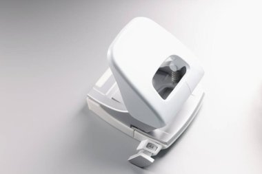 Kağıt için beyaz delik delme aracı, gri arka planda ofis aksesuarı, kullanımda basit