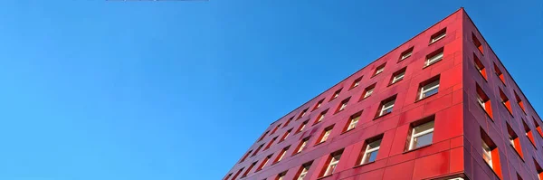 Edificio rojo de varios pisos de pie sobre fondo azul del cielo —  Fotos de Stock