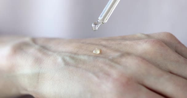 Женская рука наносит жидкую сыворотку от пипетки к коже, чтобы увлажнить кожу — стоковое видео
