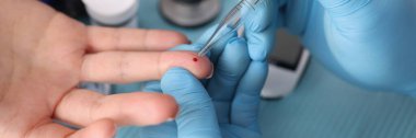Doktor laboratuvarda pipetle hasta parmağından kan testi yaptırıyor.