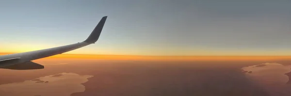 Крупним планом крило літака над землею на фоні заходу сонця — стокове фото