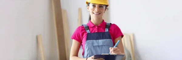 Женщина-строитель в защитном шлеме держит буфер обмена с документами — стоковое фото