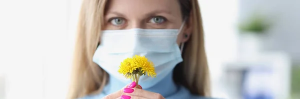Donna in maschera medica protettiva annusare fiori gialli — Foto Stock