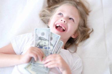 Little girl without front teeth holding money in her hands and smiling clipart