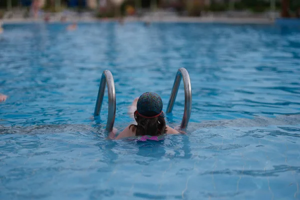 Kislány úszás medencében nyaralás vissza nézet — Stock Fotó