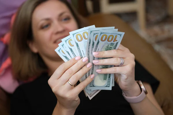 Mujer acostada en el sofá y contando un montón de billetes de dólar de cerca — Foto de Stock