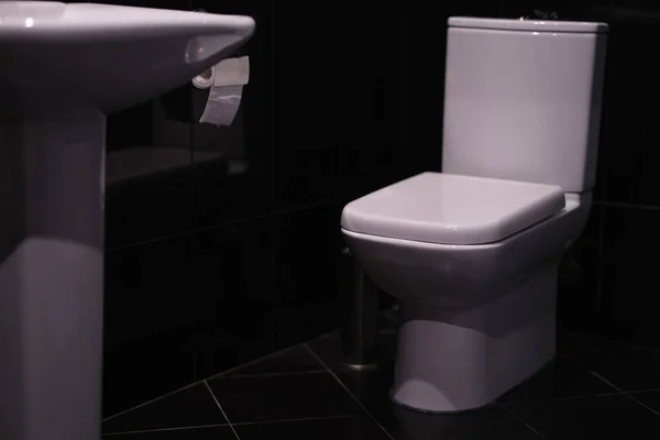 WC bianco in piedi in bagno con piastrelle nere — Foto Stock